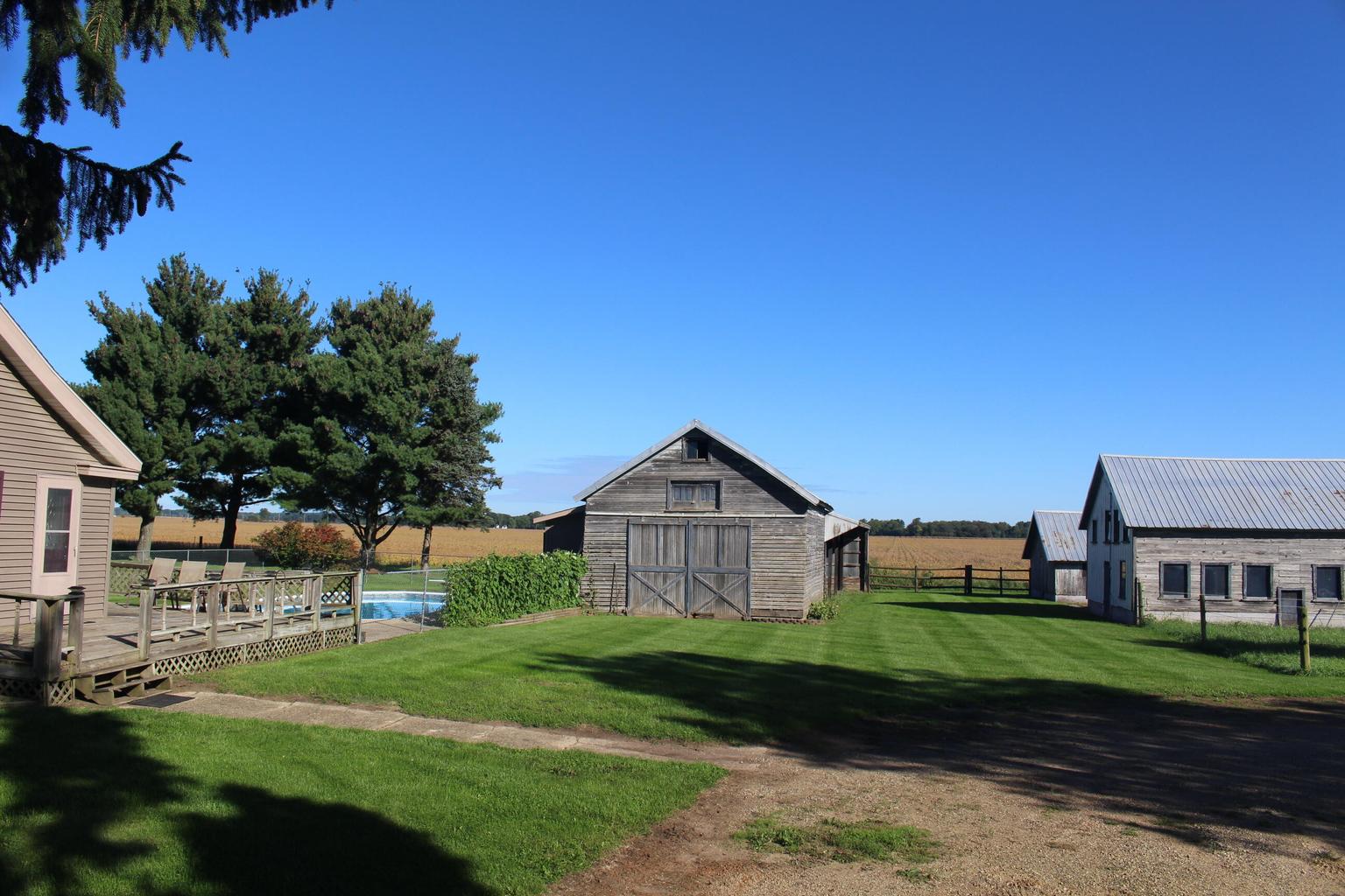 side of home with green lawn and buildings