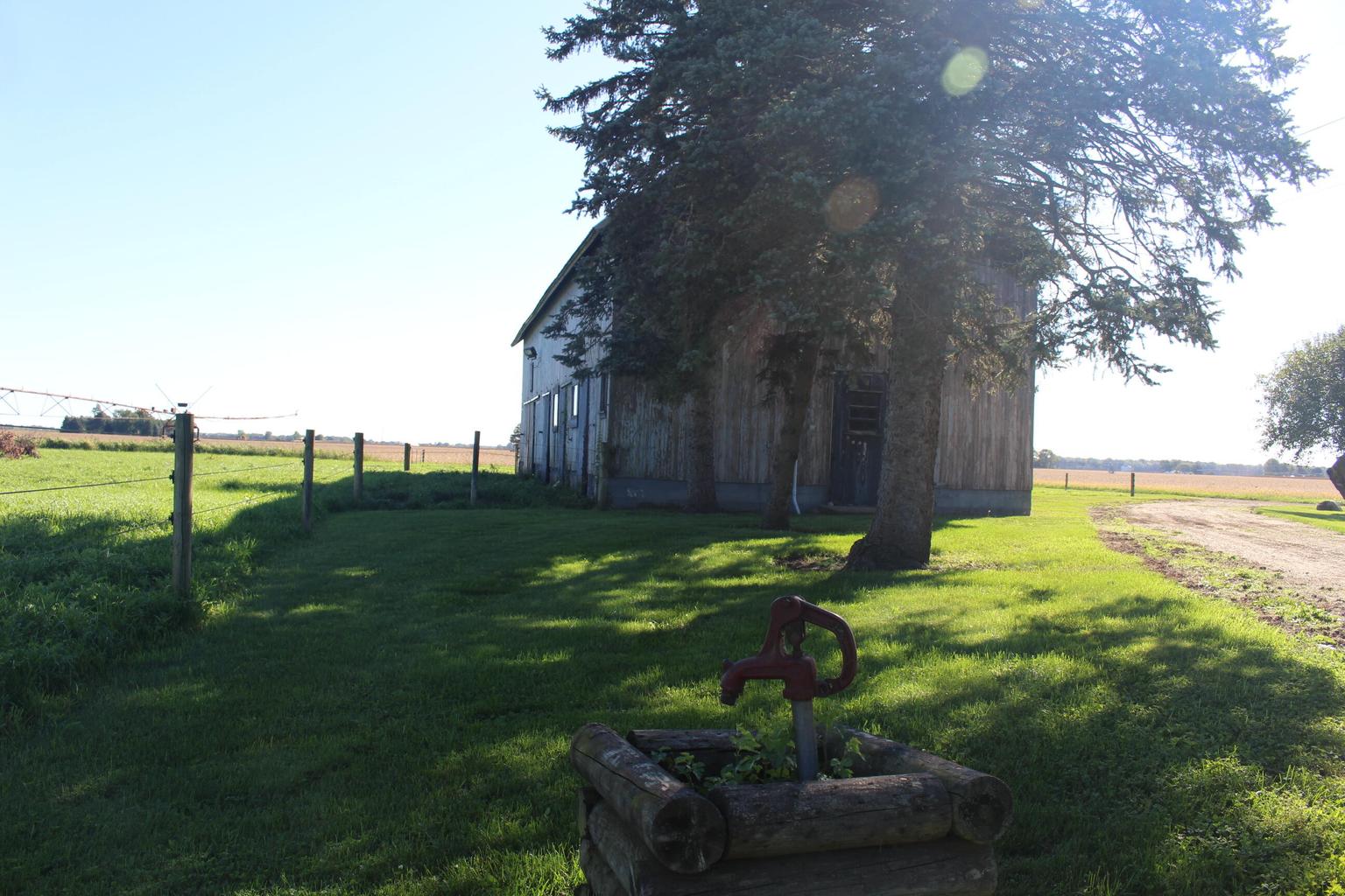 hand pump well with barn in background